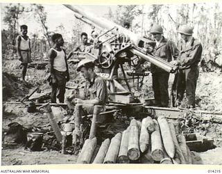 1943-01-25. PAPUA. NEARING THE END OF THE PAPUAN CAMPAIGN AGAINST JAPAN. NATIVE BOYS AND AMERICANS EXAMINE A CAPTURED 75MM. ANTI-AIRCRAFT GUN, NEAR SANANANDA. AN AUSTRALIAN TAKES ADVANTAGE OF THE ..
