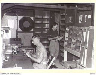 TOROKINA, BOUGAINVILLE. 1945-11-26. PRIVATE A.A. BLANK (1) AND CORPORAL R.W. HOOKE (2) WORKING IN THE RECORD LIBRARY OF RADIO STATION 9AC TOROKINA, AUSTRALIAN ARMY AMENITIES SERVICE BROADCASTING ..