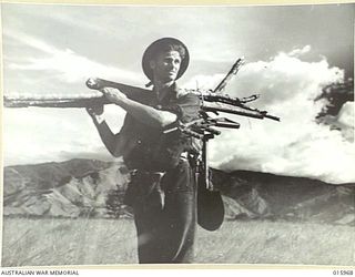 1943-10-08. NEW GUINEA. MARKHAM VALLEY. NEAR THE RAMU RIVER PTE. K.A. BOXER BRINGS IN WOOD READY TO ERECT MOSQUITO NETS. (NEGATIVE BY MILITARY HISTORY NEGATIVES)