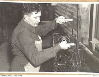 N171670 PRIVATE J.P. O'CALLAGHAN (1) OF THE TROPIC PROOFING SECTION, 1ST BASE ORDNANCE DEPOT DIPPING GEAR WHEELS IN MELTED WAX PRIOR TO WRAPPING FOR SHIPMENT TO NEW GUINEA