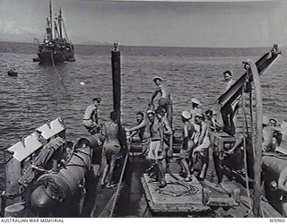 COLLINGWOOD BAY, NEW GUINEA. THE CORVETTE HMAS BROOME PREPARING TO TOW THE GROUNDED MERCHANT VESSEL COORABIE OFF A SHOAL. A TOWING HAWSER HAS BEEN PASSED BY BOAT TO THE STRANDED SHIP AND IS BEING ..