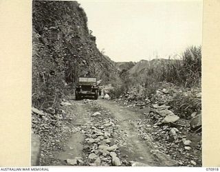 WAU - LAE ROAD, NEW GUINEA, 1944-02-26. A JEEP AND TRAILER ON A TRACK RUNNING THROUGH THE VALLEY AT MUMENG. MAINTENANCE OF THE ROAD SURFACE AT THIS AREA IS BY THE 1ST MECHANICAL EQUIPMENT PLATOON, ..