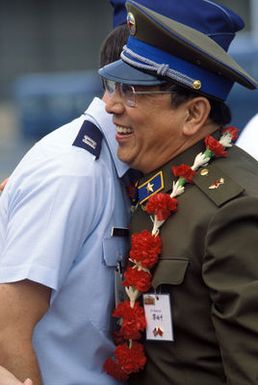 A member of the Chinese People's Liberation Army Air Force Song and Dance Troupe bids farewell to a US Air Force officer before departing for China aboard a US Air Force aircraft. The troupe performed in Hawaii on the final stop of its US tour
