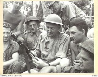 1942-10-08. THE MINISTER FOR AIR, MR DRAKEFORD, LOOKS ON WHILE MR COLES. M.H.R. EXAMINES A TOMMY GUN. (NEGATIVE BY BOTTOMLEY)