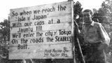 Man stands by a sign erected on Guadalcanal, 1940s