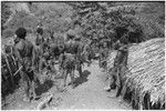 Distribution of wild pig meat: men and boys inside fence, awaiting pork