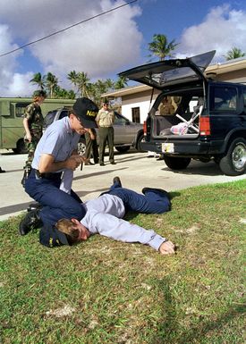 US Navy GUNNER's Mate 2nd Class (GM2) David Martino attached to Explosive Safety, Commander US Naval Forces, Marianas (ComNavMarianas) "apprehends" Electronics Technician SEAMAN Apprentice (ETSA) Doug Liembach, USN, during vehicle search drill. Agana Naval Air Station, Guam, 8 May 1998