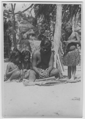 "Bock and Hessle Gilbertöarnaexpedition: 2 children and 1 young woman sitting on the ground, 1 child standing next door. All dressed petal skirts. The woman in the process of processing coconut. Text on the back: “Scraping the coconut” meat. "": Included in series with a photon. 6977: 1-15. "