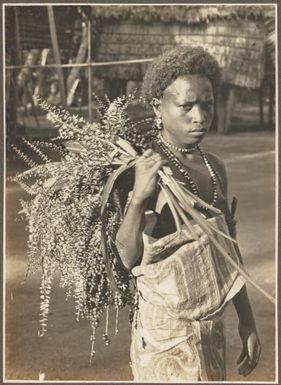 Girls Wanigella [Wanigela] village [woman carrying tree cuttings] Frank Hurley