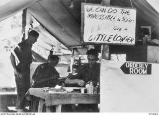 Madang, New Guinea. 1944-06-14. The tented Orderly Room at 266th Light Aid Detachment, Headquarters 15th Infantry Brigade. The unit is located at Siar Plantation. Their motto hanging outside the ..