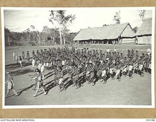 BISIATABU, NEW GUINEA. 1943-07-01. Q 186189 WARRANT OFFICER (II) T.A. BRUCE, COMPANY SERGEANT-MAJOR, "C" COMPANY, 1ST PAPUAN INFANTRY BATTALION, MARCHING "C" COMPANY OFF THE PARADE GROUND WHILE ..