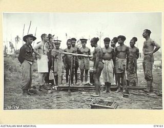 HANSA BAY, NEW GUINEA. 1944-06-19. NATIVES GATHERED AROUND A CAMP FIRE BEING INTERROGATED BY OFFICERS OF HEADQUARTERS, 5TH DIVISION