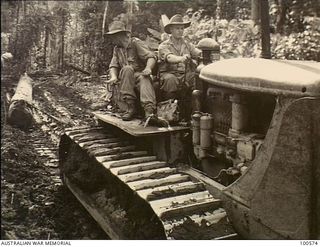 Lae, New guinea. 1944-07-26. Members of 2/3rd Forestry Company using a large tractor to drag a log out of the jungle in the Busu Forest