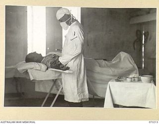 ALEXISHAFEN, NEW GUINEA. 1944-05-15. VX63770 SERGEANT J. YOUNG, MEDICAL ORDERLY, 15TH FIELD AMBULANCE (1), AT THE UNIT OPERATING THEATRE, GIVES AN INJECTION TO NX12727 CHAPLAIN F.H. PARSONS, 25TH ..