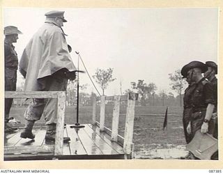 HERBERTON, QUEENSLAND. 1945-03-03. MAJOR GENERAL G.F. WOOTTEN, GENERAL OFFICER COMMANDING 9 DIVISION, (3), PRESENTING TROPHIES TO OFFICERS OF THE 24 INFANTRY BRIGADE REPRESENTING THEIR UNITS AT THE ..