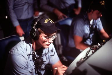 Crew members monitor radar tracking screens aboard the amphibious assault ship USS GUAM (LPH-9)