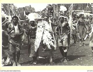 SONG RIVER, FINSCHHAFEN AREA, NEW GUINEA. 1944-03-26. MARKHAM RIVER BOYS DANCING AROUND A TOTEM POLE DURING A NATIVE SING-SING IN THE AUSTRALIAN NEW GUINEA ADMINISTRATIVE UNIT COMPOUND TO CELEBRATE ..