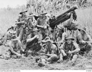KAIAPIT, NEW GUINEA. 1943-09-30 TO 1943-10-08. AUSTRALIAN TROOPS, POSSIBLY FROM 54TH BATTERY, 2/4TH FIELD REGIMENT, ENJOY A CUP OF TEA GROUPED AROUND THEIR GUN OUTSIDE RETAKEN KAIAPIT. (NEGATIVE BY ..