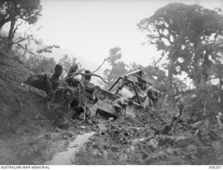REINHOLD HIGHWAY, NEW GUINEA. 1943-08-22. BULLDOZER OF THE 9TH AUSTRALIAN FIELD COMPANY, ROYAL AUSTRALIAN ENGINEERS BEING DUGOUT OF THE BENCHING AT HAINING'S CUT ABOUT THREE MILES ON THE BULLDOG ..