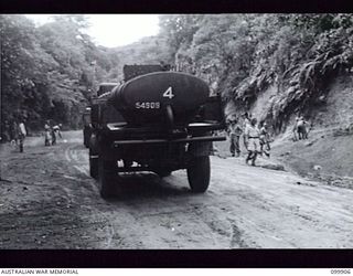 RABAUL, NEW BRITAIN, 1946-03-22. A SPRINKLER CART PREPARING THE ROAD BEING BUILT BY MEMBERS OF 51 FIELD PARK COMPANY, ROYAL AUSTRALIAN ENGINEERS, FOR THE NEXT LEVELLING BY A GRADER