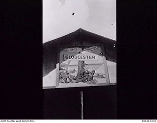 CAPE GLOUCESTER, NEW BRITAIN. 1943. CARTOON SIGN ABOVE A BUILDING AT NO. 1 WIRELESS UNIT, RAAF, DIRECTION FINDING STATION MANNED BY KANA MORSE CODE OPERATORS. THE SIGN FEATURES SIGNPOSTS POINTING ..