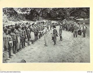 BLUP BLUP ISLAND, NEW GUINEA. 1944-06-19. NG2168 SERGEANT R. MACGREGOR, AUSTRALIAN NEW GUINEA ADMINISTRATIVE UNIT ISSUING TOBACCO TO NATIVES ON THE ISLAND IN RETURN FOR INFORMATION AND ASSISTANCE ..