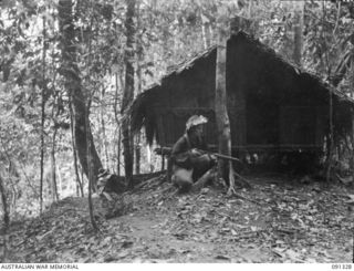 KARAWOP, AITAPE-WEWAK SECTOR, NEW GUINEA. 1945-04-29. PRIVATE E.G. NORMAN, A COMPANY, 2/1 INFANTRY BATTALION, WITH A FORWARD PATROL SEARCHING OUTSIDE ABANDONED JAPANESE HUTS