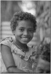 Young girl smiling, wearing a small shell bead necklace