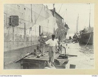 LAE, NEW GUINEA. 1944-09-29. AUSTRALIAN TROOPS, WITH INDIAN TROOPS WHO WERE PRISONERS OF WAR OF THE JAPANESE, CARRYING FOOD ASHORE FOR A PICNIC ARRANGED FOR THEM BY MEMBERS OF THE AUSTRALIAN RED ..