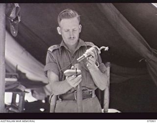 HANSA BAY AREA, NEW GUINEA. 1944-09-05. QX51714 LIEUTENANT F V HILL, D COMPANY, 25TH INFANTRY BATTALION EXAMINING THE FIRING MECHANISM OF A JAPANESE BANGALORE TORPEDO WHICH WAS CAPTURED COMPLETE IN ..