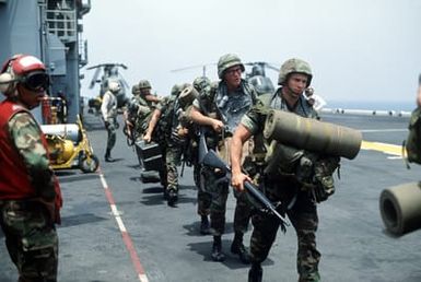 Marines of the 22nd Marine Expeditionary Unit (22nd MEU) are led to a helicopter on the flight deck of the amphibious assault ship USS SAIPAN (LHA-2) during a rehearsal for Operation Sharp Edge. The SAIPAN is on station off the coast of Liberia