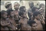 Dance: children with painted faces and shell necklaces observe a dance