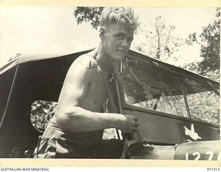 RAMU VALLEY, NEW GUINEA, 1944-03-21. VX44871 PRIVATE D.J. ATHERTON (1), OF HEADQUARTERS, 7TH DIVISION, CLEANING A JEEP