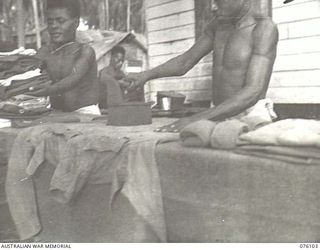 KARKAR ISLAND, NEW GUINEA. 1944-09-20. NATIVE HOUSEBOYS DOING THE IRONING AT A HOUSE OCCUPIED BY MEMBERS OF THE AUSTRALIAN NEW GUINEA ADMINISTRATIVE UNIT