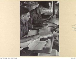 CAPE WOM, NEW GUINEA. 1945-10-17. PRIVATE F.N. VIRGONA (1) AND PRIVATE C.R. MARKS (2), CLERKS OF HEADQUARTERS 6 DIVISION HANDLING DEMOBILIZATION RETURNS WHICH COME IN FROM VARIOUS UNITS IN THE ..