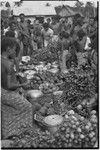 Mortuary ceremony: men with piles of yams, taro, and betel nut to be distributed to mourners