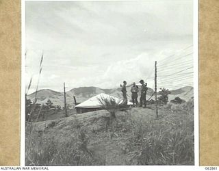 DUMPU, NEW GUINEA. 1944-01-11. EXTERIOR VIEW OF THE 7TH DIVISION SIGNALS WIRELESS TELEPHONE RECEIVING HUT. SHOWN ARE: VX8245 LIEUTENANT E. R. BLACKFORD (1); VX15114 SERGEANT W. J. EDWARDS (2); ..