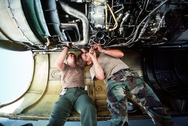 AIRMAN 1ST Class Homer Shumake, left, and AIRMAN 1ST Class Terry Price, maintenance specialists with the 320th Bomb Wing, repair an engine on a B-52 Stratofortress aircraft during Exercise Giant Warrior '89