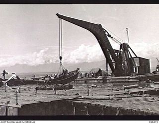 LAE, NEW GUINEA. 1943-10-13. LARGE FLOATING CRANE OF THE UNITED STATES SMALL SHIPS SECTION, RAISING A SUNKEN JAPANESE BARGE FROM THE DOCK AREA