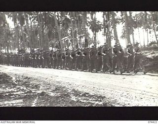 MADANG, NEW GUINEA. 1944-06-30. MEMBERS OF D COMPANY, 24TH INFANTRY BATTALION MARCHING ALONG A ROAD NEAR THE UNIT CAMP. IDENTIFIED PERSONNEL ARE:- VX104144 MAJOR S.H. WHITELAW (1); VX104471 WARRANT ..