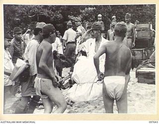 FAURO ISLAND, BOUGAINVILLE AREA. 1945-10-01. LIEUTENANT GENERAL H. HYAKUTAKE, COMMANDER 17 JAPANESE ARMY, SALUTES AUSTRALIAN OFFICERS AS HE IS CARRIED ASHORE ON FAURO ISLAND. ALL JAPANESE MEDICAL ..