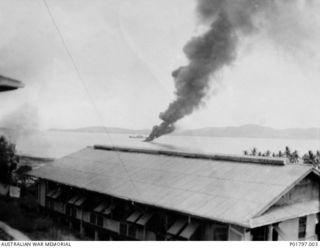 Port Moresby, Papua, 1942-02-28. A thick pall of smoke rises from a RAAF Consolidated Catalina aircraft, burning at its mooring in Port Moresby harbour after being hit by a bomb during a Japanese ..