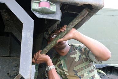 US Marine Corps (USMC) Sergeant (SGT) Hart, assigned to Combat Service Support Group 3 (CSSG-3), Marine Forces Pacific (MARFORPAC) performs maintenance on a transport truck hinge, while loading equipment at Camp H.M. Smith, Hawaii (HI), as the Unit prepares for deployment to Iraq, in support of Operation IRAQI FREEDOM