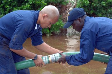 US Navy (USN) PETTY Officers (PO) Alex Shafer (left) and Claude Ngouan, assigned to the USN Ticonderoga Class Guided-missile Cruiser USS LAKE ERIE (CG 70) connect two discharge hoses during a deflooding operation on the flood-stricken Hawaiian island of Kauai