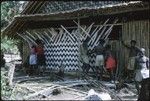 Men plaiting a wall of a house