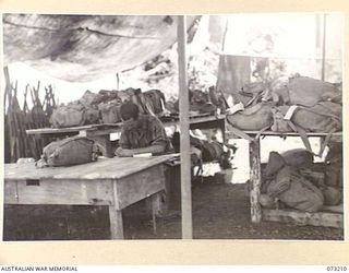 ALEXISHAFEN, NEW GUINEA. 1944-05-15. VX70533 PRIVATE A PETERSON (1), INDENTING PACKS IN THE TEMPORARY PACK STORE AT THE 2/15TH FIELD AMBULANCE. THE STORE, USED TO STORE THE PERSONAL PACKS OF ..