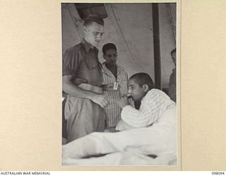 BORAM BEACH, NEW GUINEA. 1945-10-17. LANCE CORPORAL SHAR SINGH, 2/12TH F.F. REGIMENT, AN INDIAN SOLDIER LIBERATED IN THE SEPIK RIVER AREA AND BROUGHT TO WEWAK FOR TREATMENT, TAKING HIS MEDICINE ..