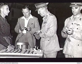 LAE, NEW GUINEA, 1946-01-27. THE HONOURABLE F. M. FORDE, MINISTER FOR THE ARMY, (2) PURCHASING A WATCHBAND FROM CORPORAL W. R. RIGBY (1) DURING HIS VISIT TO THE OTHER RANKS' CLUB. MR FORDE, WHO IS ..