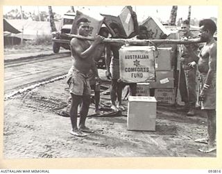 WEWAK AREA, NEW GUINEA, 1945-07-05. NATIVES PREPARING FOR THE LONG TREK INTO THE HILLS WITH AUSTRALIAN COMFORTS FUND HAMPERS WHICH ARE BEING PROVIDED BY THE AUSTRALIAN COMFORTS FUND, LAE ..