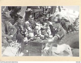 BOIKEN, NEW GUINEA. 1945-07-18. GUNNERS OF 2/2 FIELD REGIMENT, ROYAL AUSTRALIAN ARTILLERY, RESTING ON THE BEACH LISTENING TO A GRAMAPHONE WHICH IS TAKEN AROUND TO ALL UNITS IN THE AREA BY THE YMCA